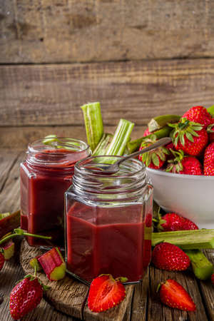 Homemade strawberry rhubarb jam or sauce, with fresh rhubarb and strawberries and spices, wooden rustic background copy space の写真素材