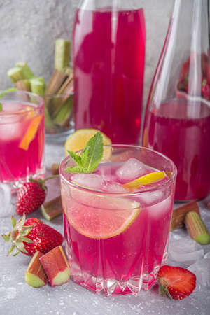 Homemade rhubarb and strawberry alcohol cocktail. Rhubarb liquor or gin, on a gray background with fresh rhubarb, strawberries, lemon, mintの写真素材