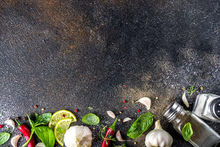 Assortment of spices, herbs and greens. Ingredients for cooking. Food background. Black stone table,...