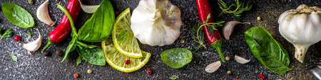 Assortment of spices, herbs and greens. Ingredients for cooking. Food background. Black stone table, Copy space for text. Top view.の写真素材