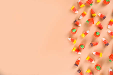 Candy corn sweets and pumpkin candies layout on peach autumn background flat lay copy space. Traditional autumn Halloween and Thanksgiving sweetsの写真素材
