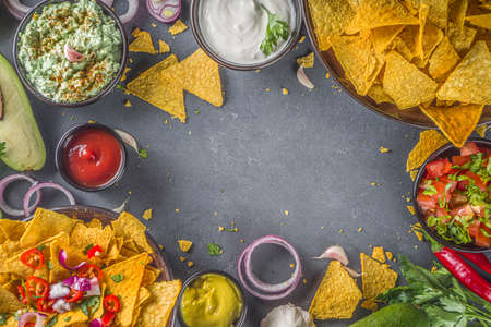 Nachos chips with melted cheese and various traditional mexican dips, salsa and jalapeno, dark grey background top view copy spaceの写真素材
