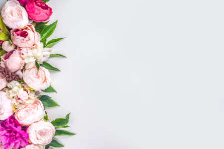 Flat lay of flowers and green leaves. Tender Peonies and chrysanthemums bloom pattern, composition for postcards on white background.