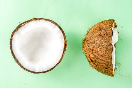 Raw fresh coconut isolate on a white background. Half of coconuts on a light green tableの写真素材
