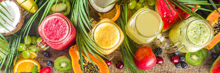 Assorted different fruit smoothies and juices with tropical fresh fruits and berries. Clean eating, healthy lifestyle, diet and vitamin drink beverages concept. Top view flatlay white table background の写真素材