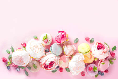 Colorful french macaron dessert. Set of various different tastes and color macaron cookies with berries, flowers, sugar powder and mint on pink backgroundの写真素材