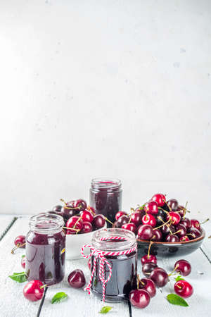 Jar of cherry jam. Homemade sweet and sour cherry jam with fresh cherries on wooden white table, copy spaceの写真素材