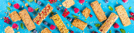 Healthy snack concept,  Cereal granola bars with fresh berries and nuts on blue background copy spaceの写真素材