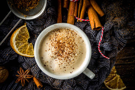 Autumn sweet hot drink, Chai Buttered Rum, Pumpkin Pie or Pumpkin Spice Coffee Latte. Cozy autumn background with traditional latte cup, spices and old sweater, on rustic wooden backgroundの写真素材