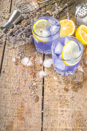Lavender alcoholic cocktail, Lavandula lemonade with lemon and honey, on wooden background with lavender bunch and barmen utencils, copy spaceの写真素材