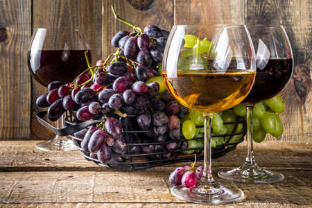 Glasses with wine. Red and white wine in glasses with grape on wooden background copy spaceの写真素材