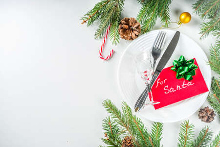 Christmas festive table setting with with a plate, fork, Christmas decorations, gift boxes, fir tree...