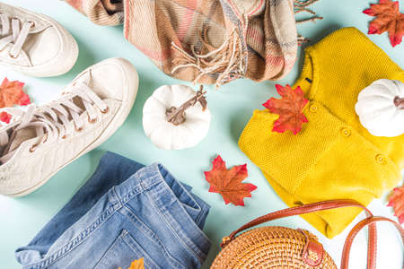 Autumnal clothes set. Cozy casual trendy woman clothing and shoes - jeans, sweater, bad, sneakers. Set of seasonal autumn fashion female clothes, top view copy spaceの写真素材