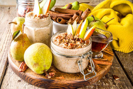 Sweet and spicy autumn breakfast oats recipe, Homemade pear and cinnamon overnight oatmeal with spices and yogurt, wooden background copy spaceの写真素材