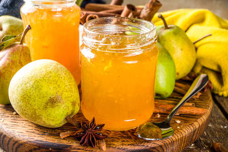 Homemade sweet and spicy pear jam. Different glass jars with pear jam, on wooden background with fresh pears and spicesの写真素材