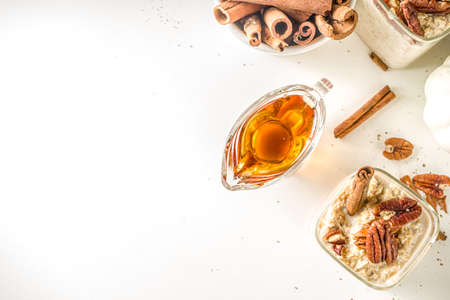 Spice autumn breakfast oats recipe, Homemade maple cinnamon overnight oatmeal with pecan nuts, maple syrup and spices, copy spaceの写真素材