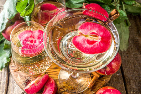 Apple cider drink. Autumn red apples cider martini cocktail, with apple slices and fresh sliced apples, wooden background copy spaceの写真素材