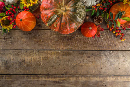 Festive autumn background, with traditional decor - pumpkins, berries, fruits, leaves on old wooden background. Thanksgiving day and Halloween holiday greeting card concept. Autumn flatlayの写真素材