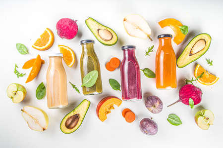 Fruit and vegetable smoothie concept. Portioned bottles with fruit and vegetable smoothies flatlay with fresh ingredients on white table backgroundの写真素材