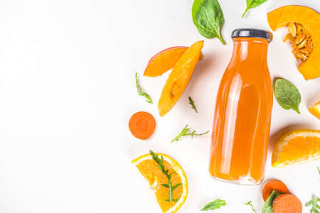 Orange healthy smoothie bottles with ingredients. Vegetable smoothie or juice with carrot, pumpkin, oranges, white table background, flatlay copy spaceの写真素材