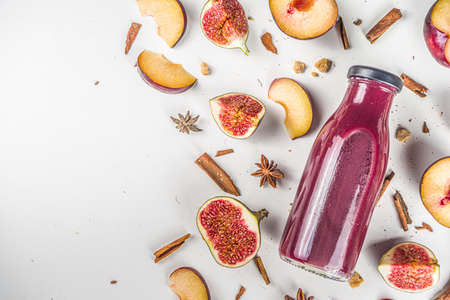 Autumn fruit red smoothie in small portioned bottle. figs and plums smoothie, with autumn traditional spices, flatlay on white backgroundの写真素材