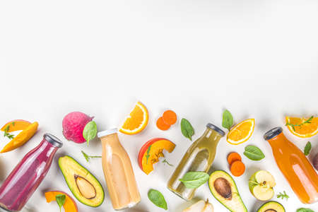 Fruit and vegetable smoothie concept. Portioned bottles with fruit and vegetable smoothies flatlay with fresh ingredients on white table backgroundの写真素材