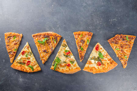 Various italian american traditional pizza slices. Slices of delicious pizza on dark gray concrete background, top view flatlayの写真素材