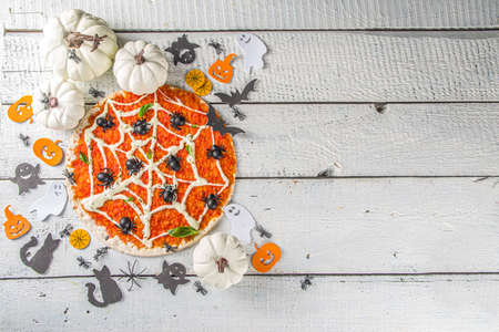 Halloween funny pizza. Halloween party recipe, Creative idea for Halloween pizza`s with ham and cheese ghosts, monster, spiders, white wooden background with Halloween decorationsの写真素材