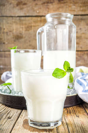 Cold Indian drink Lassi, iced coconut Lassi drink with mint leaf, wooden background copy space