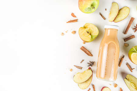 Apple and pear smoothie in small portioned bottle, with fresh autumn traditional spices, flatlay on white backgroundの写真素材