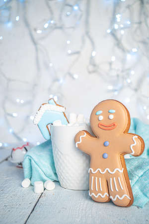 White Christmas concept, greeting card background. Winter hot chocolate drink with cute homemade gingerbread cookies, gingerbread man, on white background with festive garlandの写真素材