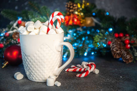Dark Christmas festive background with xmas decoration, hot chocolate cup with candy cane and...