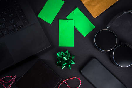 Christmas Clearance and Sale Concept. Black Friday, Green Monday (Cyber Monday) Sale. With Discount Price Tags, Black gadgets and accessories, Shopping Bag. Flat lay top view, black matte backgroundの写真素材