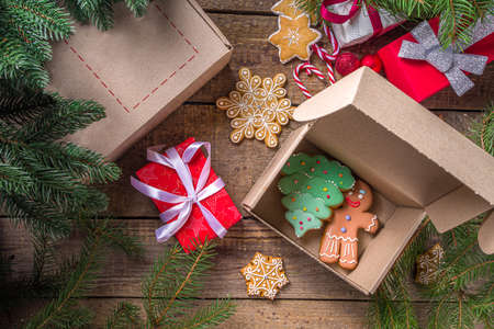 Christmas Gift Box package. Gift exchange Christmas New Year concept on covid-19 pandemic. Secret Santa post game. Packing gifts, cookies in parcel. Wooden background, with Xmas tree branch and decorの写真素材