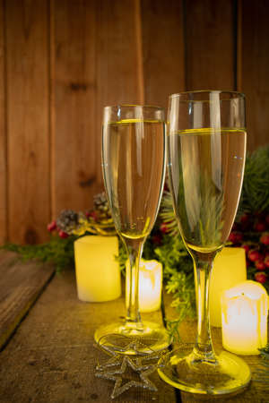 New Years Christmas celebration background. Two glasses with champagne on wooden background of christmas decor and baubles copy spaceの写真素材