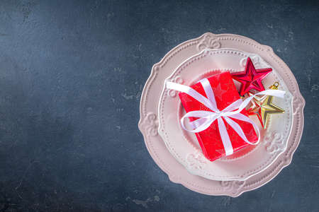 Christmas table setting with plates, champagne glass, Christmas gift boxes and decoration, fir tree branches, over black concrete background copy space top viewの写真素材