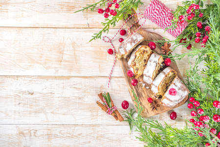 Christmas stollen with icing sugar, marzipan and raisins. Traditional Dresden christ pastry. On table background with fir tree branches and Christmas decoratioon top view copy spaceの写真素材