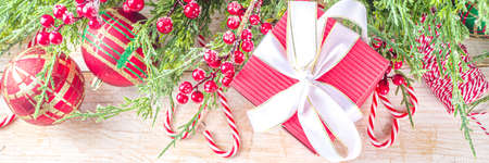 Festive Xmas background with fir tree branches, red winter berries, candy cane decoration and...