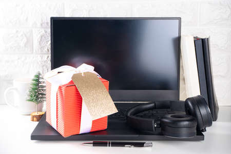 Secret Santa. Christmas celebration in office. Office desk with laptop, notepads, office supplies, smartphone and large Christmas gift box with festive bow. flatlay copy spaceの写真素材