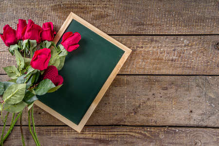 Red rose flowers bouquet with red heart on wooden background. Valentine's day greeting card background. Copy space Top viewの写真素材