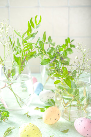 Spring nature revival concept. Green plants and wild garden flowers in different glasses and jars on a green background, house interior, copy space for for text Spring floral composition.の写真素材
