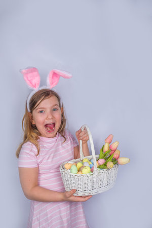 Happy cute girl with bunny ears. Easter greeting card background. with Easter eggs and spring flower...