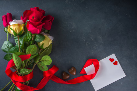 Valentines day greeting card concept with red rose flowers, champagne, chocolates and gift box. Top view flat lay on black concrete background with space for greetingsの写真素材