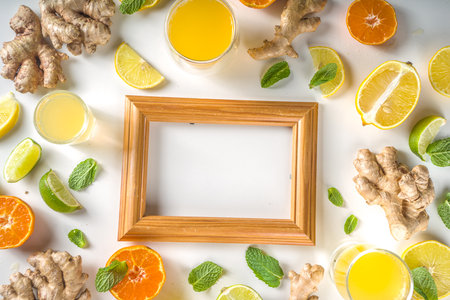 Immunity booster drink ingredients. Homemade ginger and citrus juice or cocktail, with fresh citrus fruit - orange, lemon, lime, with ginger root and mint leaves. White background top view copy spaceの写真素材