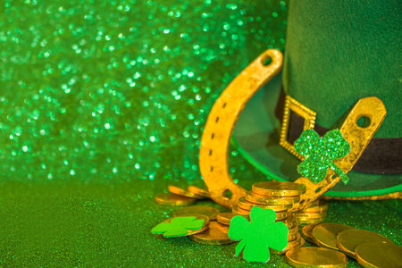 Saint patrick's day greeting background. Patrick's day sale, invitations template, menu. With holiday symbols - golden horseshoe, green clover, leprechaun hat, gold coins, green bokeh backgroundの写真素材