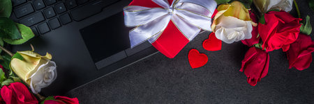 Valentine day greeting card with red rose flowers bouquet, wine and gift box on black table table. Top view with space for greetingsの写真素材