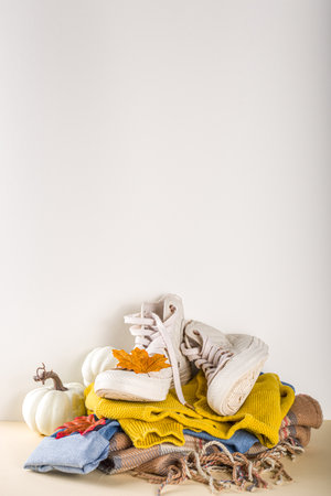 Autumnal clothes set. Cozy casual trendy woman clothing and shoes - jeans, sweater, bad, sneakers. Set of seasonal autumn fashion female clothes, top view copy spaceの写真素材