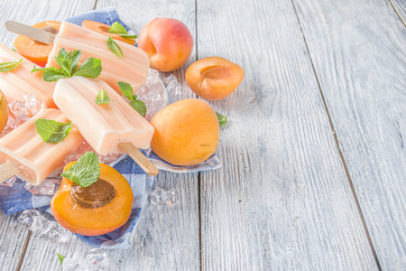 Homemade peach ice creams, fruity lollypop non-dairy vegan gelato, on gray old wooden background copy space top viewの写真素材