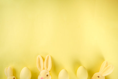 Easter trendy  2021 flat lay pattern. Easter card, sale, invitation background. Yellow bunny rabbits, with yellow Easter painted eggs, on yellow background top view with copy spaceの写真素材
