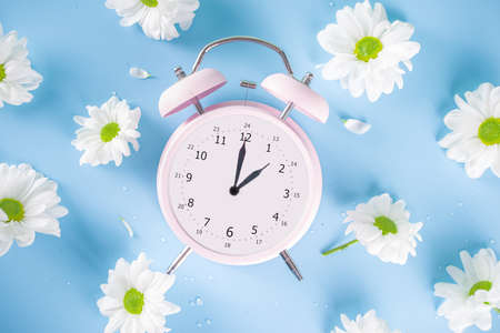 Spring Time Change flatlay. Summer back concept. Retro Vintage alarm Clock with fresh, beautiful...